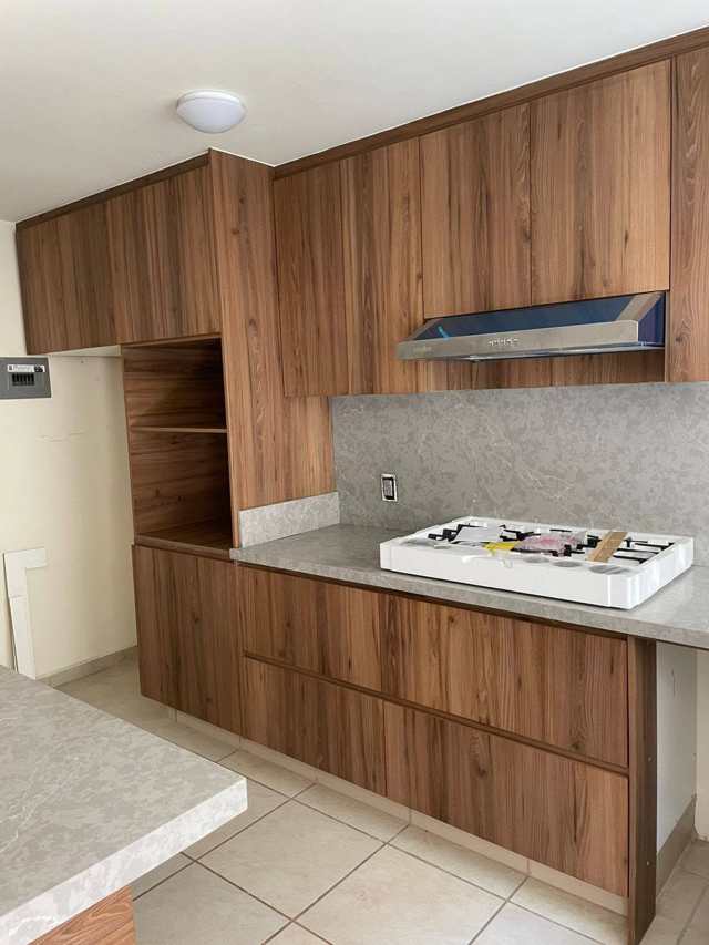 Cocina integral en nogal con cubierta de cuarzo claro, proyecto entregado en Guadalajara